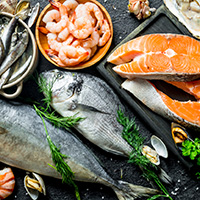 Fresh salmon steak with a variety of seafood and herbs. On black rustic background