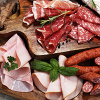 Food tray with delicious salami, ham,  fresh sausages and herbs. Meat platter with selection.