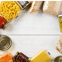 Various uncooked cereals, grains, pasta and canned food on a white wooden table. Ingredients for cooking. Frame background with copy space.