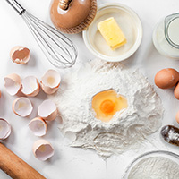 white background with fresh eggs , eggshell , butter , flour ,sugar and rolling pin